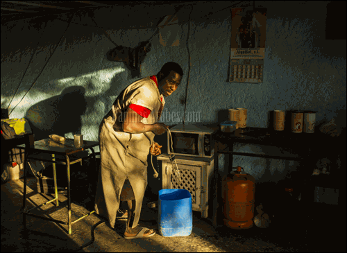 Un trabajador lleva un cubo de agua a la cocina de un cortijo abandonado en el que vive en Níjar, Almería ©Santi Palacios